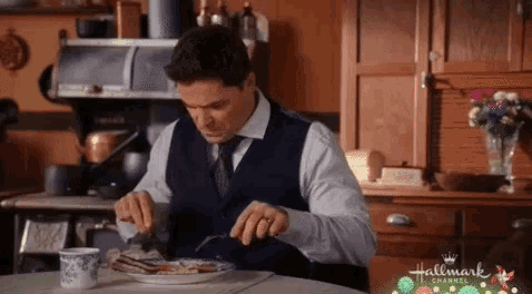 a man is sitting at a table eating a plate of food .