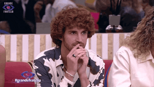 a man with curly hair is sitting in front of a large eye