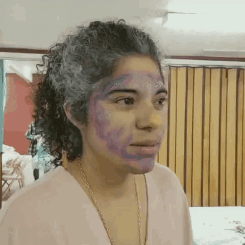 a woman with gray hair and a purple face paint on her face .