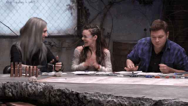 a group of people are sitting around a table playing a game and one of them is holding a gun