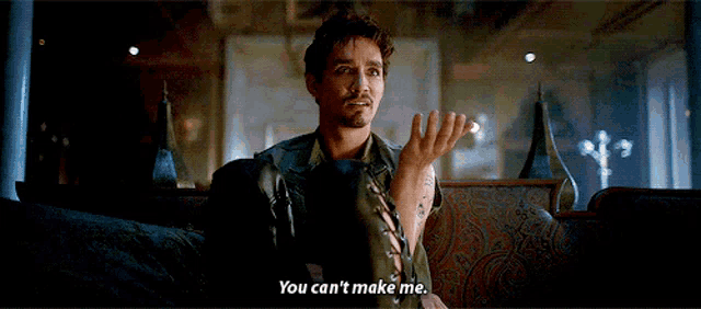 a man is sitting on a couch and saying you can 't make me .