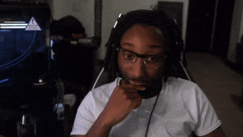 a man wearing glasses and headphones is sitting in front of a sign that says caution