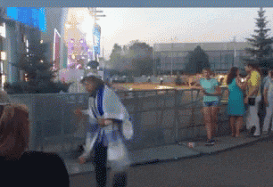 a blurred image of people standing on a sidewalk in front of a building
