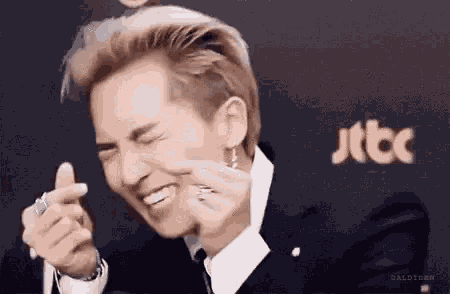 a man in a suit and tie is making a funny face while pointing at the camera .