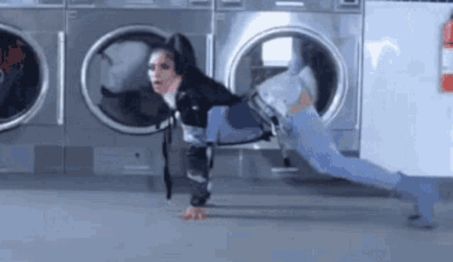 a woman is doing a split in front of a washing machine