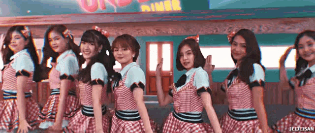 a group of girls are dancing in front of a diner