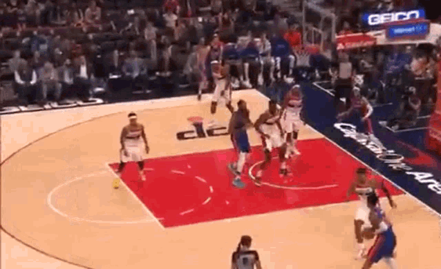 a group of basketball players are playing a game on a court sponsored by geico