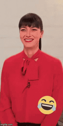 a woman in a red shirt is laughing with a yellow smiley face behind her .