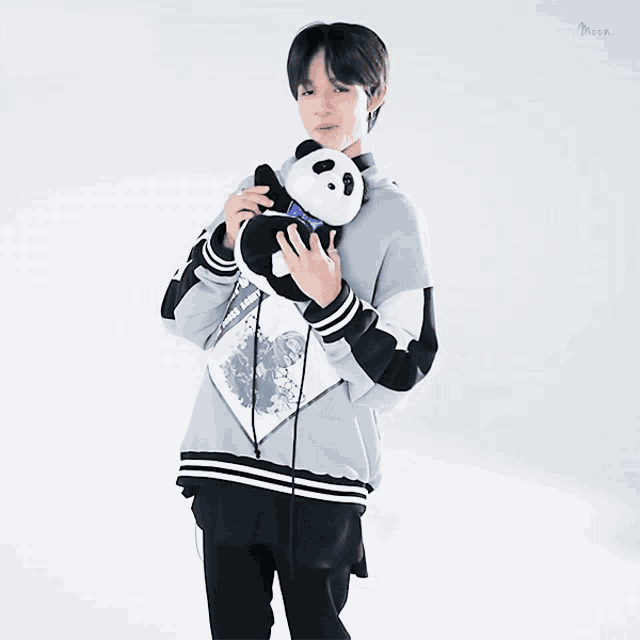 a young man holding a stuffed panda bear with a blue bow tie