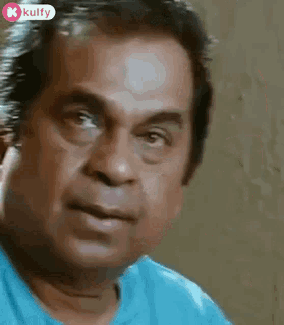 a close up of a man 's face with a blue shirt on .