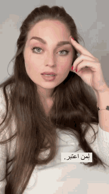 a woman with long brown hair and red nails is wearing a bracelet
