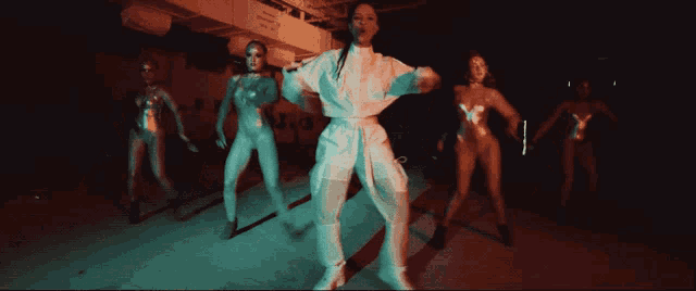 a group of women are dancing in a dark room with a sign that says ' a ' on it