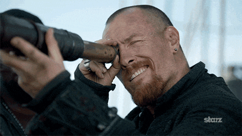 a man looking through a telescope with a starz logo on the bottom