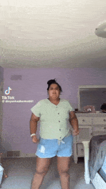 a woman is dancing in a bedroom in front of a mirror and dresser .
