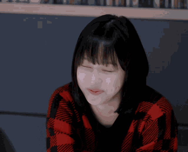 a woman wearing a red and black plaid sweater makes a face