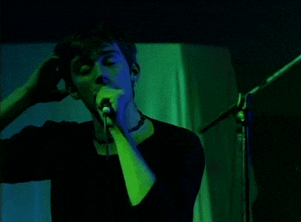 a man is singing into a microphone in a dark room with green and blue lights .