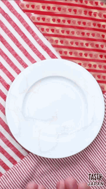 a white plate is sitting on a red and white striped table cloth that says tasty japan on it