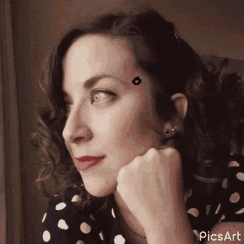a woman in a black and white polka dot dress has a tattoo on her forehead that looks like a kiss