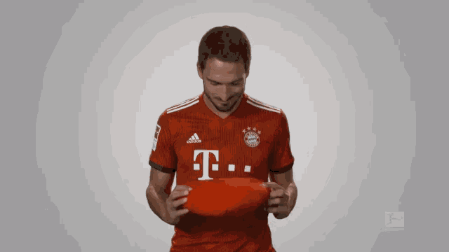 a man wearing a red adidas shirt holds a red object