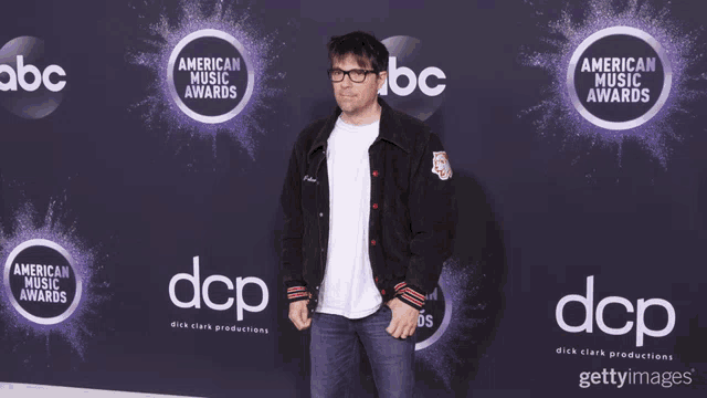 a man stands on a red carpet with abc and dcp logos