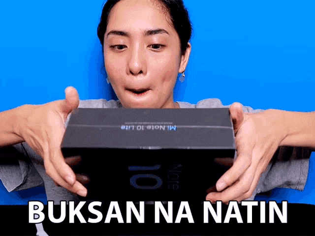 a woman is holding a mi note 10 lite box in her hands