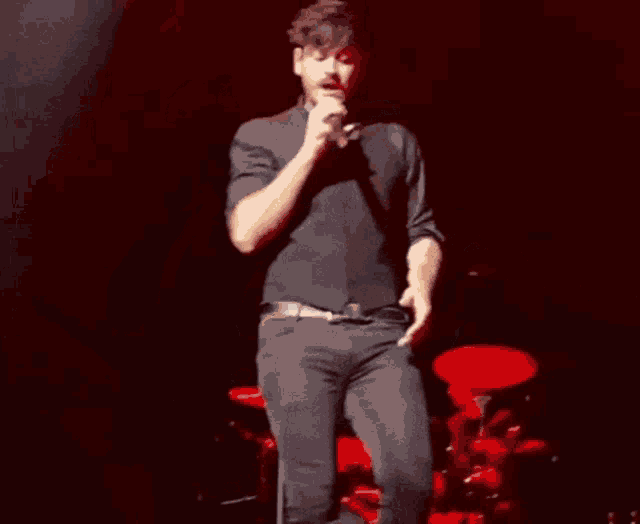 a man is singing into a microphone on stage .