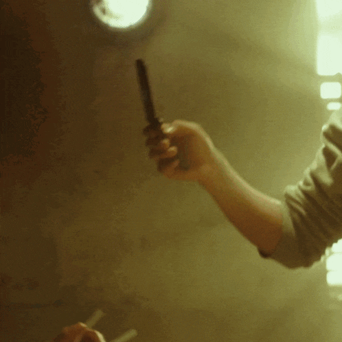 a person holding a knife in their hand in front of a window
