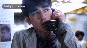 a man is talking on a phone in front of a newspaper .