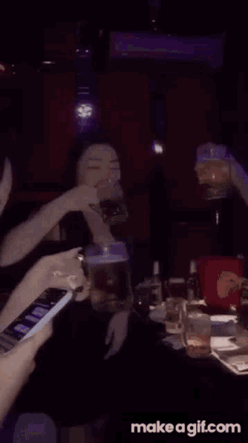a group of people are standing around a table in a dark room holding phones .