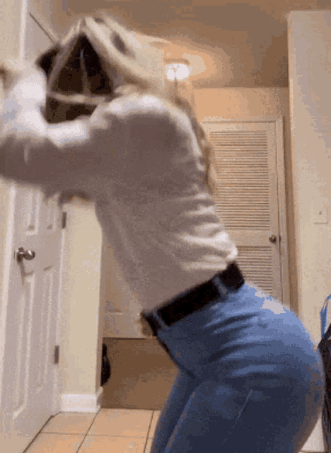 a woman in a white shirt and blue jeans is squatting down