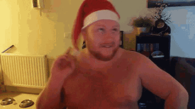 a shirtless man wearing a red santa hat