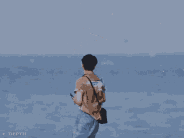 a man is standing on a beach looking at the ocean