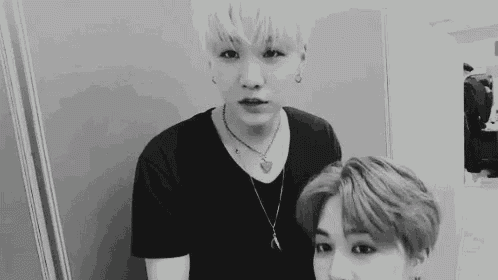 a black and white photo of two young men standing next to each other in a room .