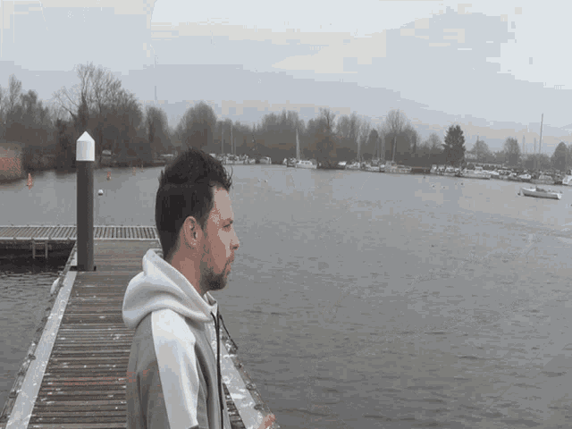 a man is standing on a dock looking at the water