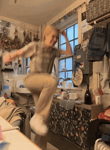 a person is jumping in the air in a kitchen with a sign on the wall that says ' i love you ' on it