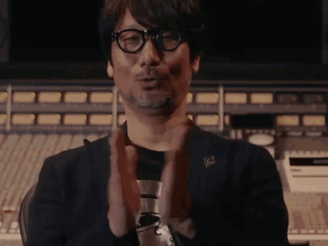 a man wearing glasses is clapping his hands in front of a computer