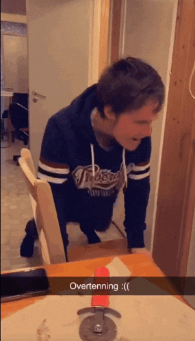a man wearing a hoodie that says tigers is kneeling down