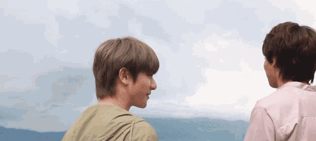 two young men are standing next to each other and looking at each other .