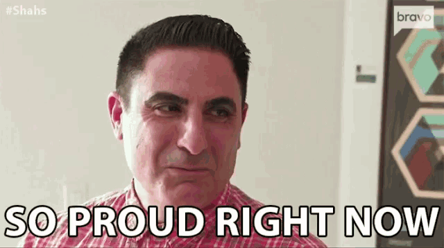a man is smiling and saying `` so proud right now '' while wearing a plaid shirt .