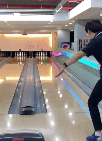 a man throws a bowling ball in a bowling alley that has the number 12 on it