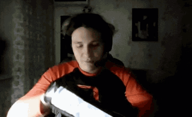 a man wearing a headset and a red shirt is holding a remote control