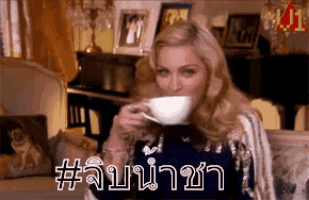 a woman is drinking a cup of tea in a living room