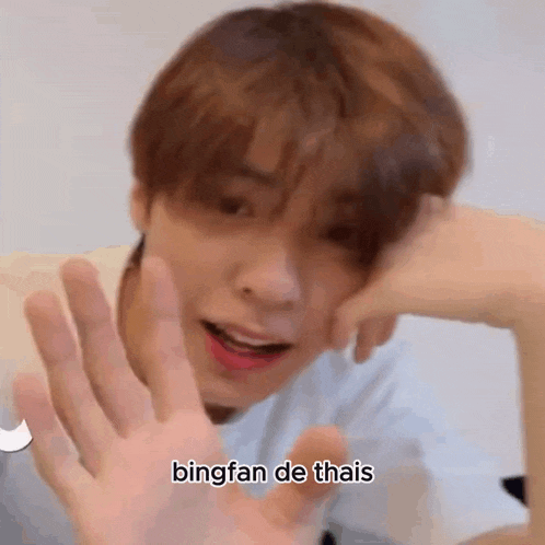 a close up of a person 's face with their hand up and the words `` bingfan de thais '' written on it .