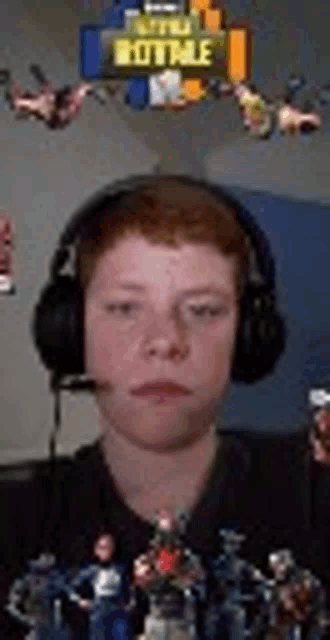 a young boy wearing headphones and a microphone is sitting in front of a bunch of toy figures .