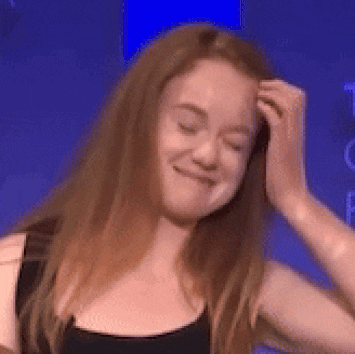 a woman with long red hair is smiling while holding her hair .