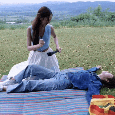 two women laying on a blanket in the grass