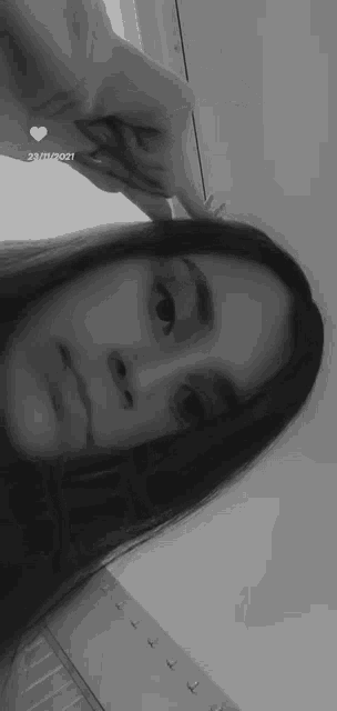 a black and white photo of a girl taking a selfie with her finger in her hair .
