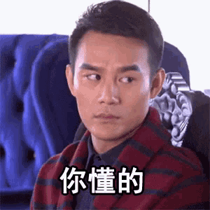 a man in a plaid jacket is sitting in a chair and making a face .