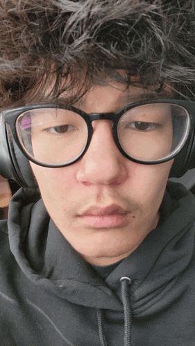 a young man wearing glasses and headphones looks tired