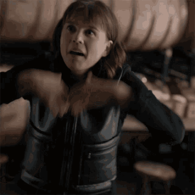 a woman in a black leather vest is making a face